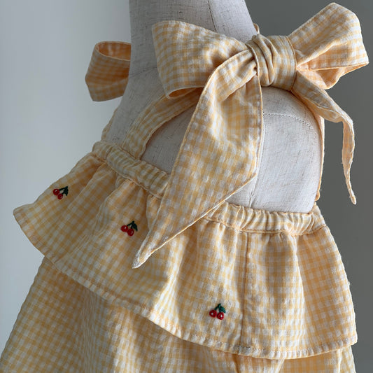 Castille Top on mannequin, baby girl yellow gingham cotton top, cherry embroidery, bow detail straps  — Willowby, sizes 6–18 months