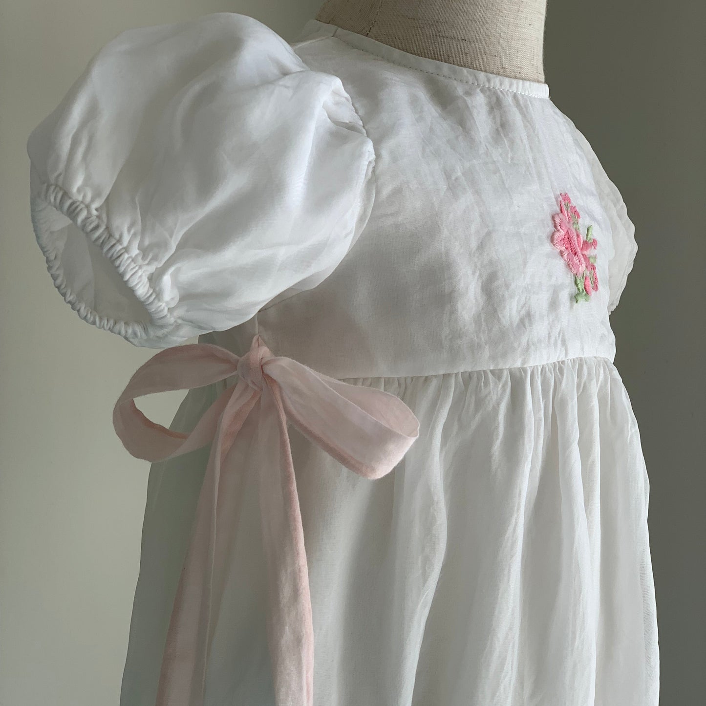 Rose Romper on mannequin close up, , baby girl romper, puff sleeve, bow detail and embroidery — Willowby, sizes 6–18 months